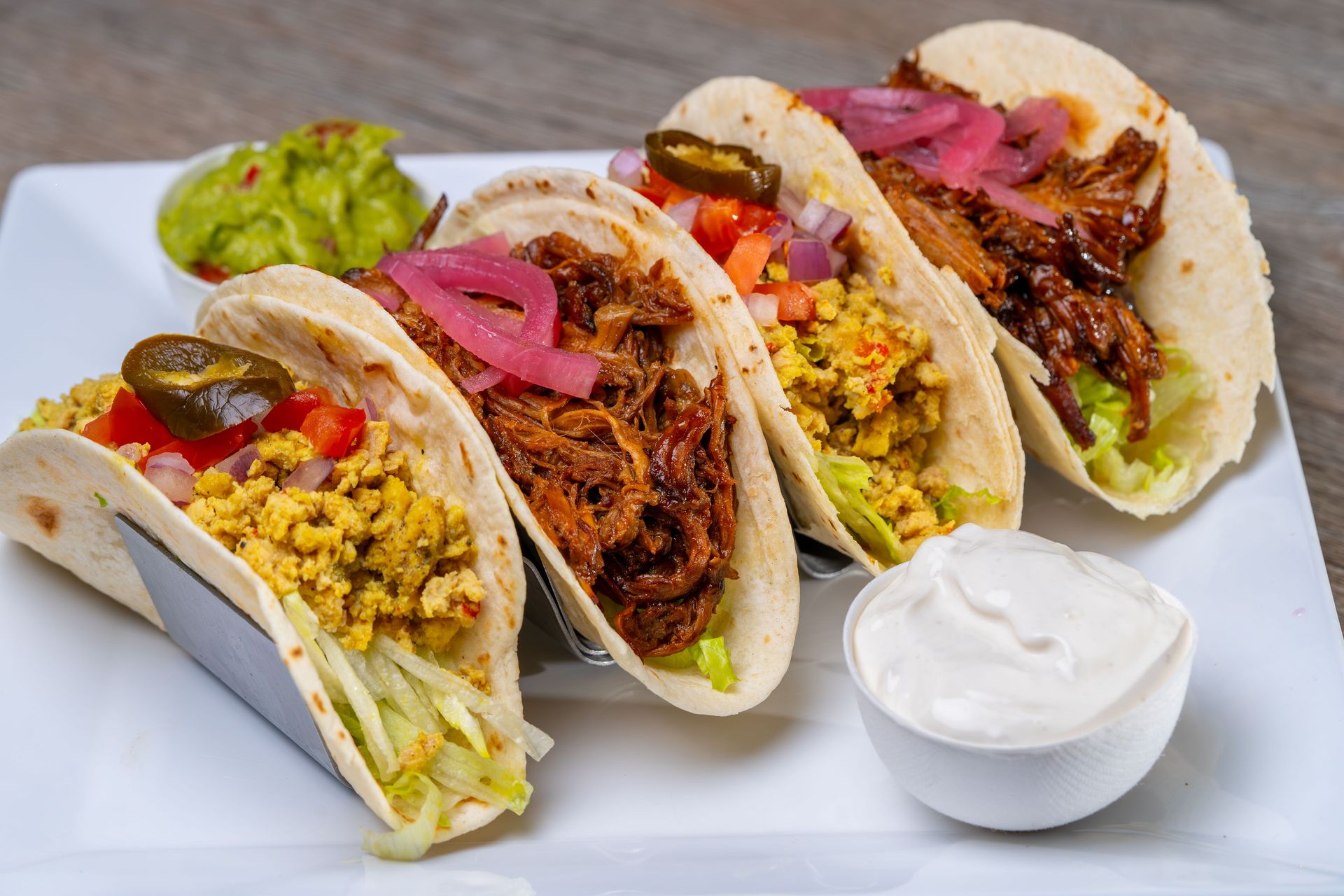 Appetizing tacos with shredded meat and scrambled eggs, served with guacamole and sour cream.