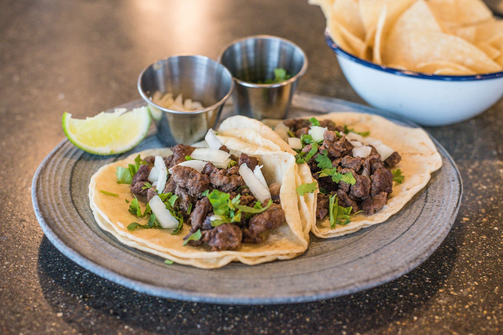Close-up of beef tacos with cilantro and lime on a plate, showcasing Mexican cuisine.